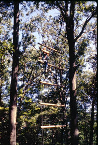 Student sitting on high ropes course ladder at East Campus