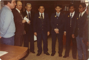 Photograph of a group of men posing during a check giving event, [1982-1983].