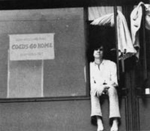 A male student in a window with a "coeds go home" sign