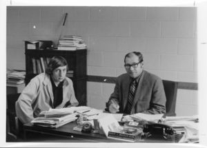 Suffolk University Professor Robert C. Waehler (SBS) and Dean (1969-1974), seated behind desk, with student