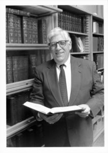 Suffolk University Professor Brian T. Callahan (Law), beside bookshelf with book in hands