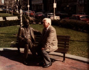 Thomas P. O'Neill seated next to statue of James Michael Curley