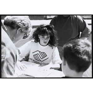 A female staff member wearing a Boys and Girls Clubs of Boston t-shirt works outside at the Boys and Girls Clubs of Boston 100th Anniversary Celebration Street Fair