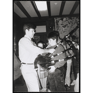 John Harrington, Charlestown Boys and Girls Club member, blowing into a bagpipe while an instructor holds it
