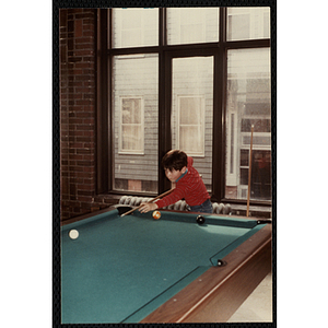 A Young boy taking his turn in a pool game