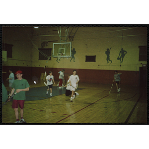 Teenagers play floor hockey in a gymnasium