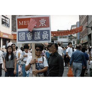 Woman holds a Mel King campaign sign written in Chinese during the August Moon Festival in Boston's Chinatown