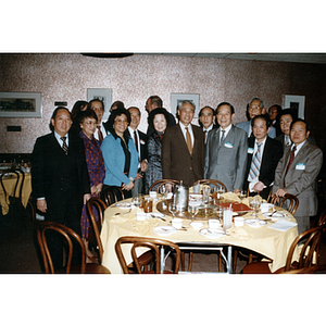 Members of the Chinese Progressive Association stand around a restaurant table with visiting Chinese diplomats