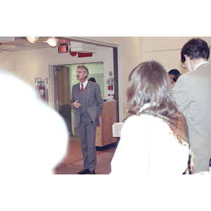 Man stands and addresses a group of onlookers during a food tasting event