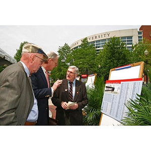 Three men converse while looking at plans for the Veterans Memorial at the groundbreaking ceremony
