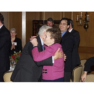 John Hatsopoulos hugs a woman at a gala dinner in his honor