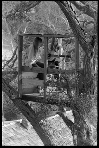 Joni Mitchell seated in her tree house in Laurel Canyon with Judy Collins, with guitar