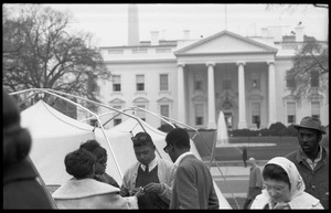 Strikers and supporters milling about outside a tent, the White House in the background