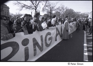 Protestors holding flags and a large sign reading, 'bring all the troops home now'