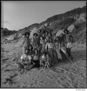 Ram Dass and Satsang: Ram Dass posing on the beach with a group including Ronni Simon at right, Tukaram Das at back center, Daniel Goleman at back left, and Mirabai Bush and Chaitanya Maha Prabu seated at center front
