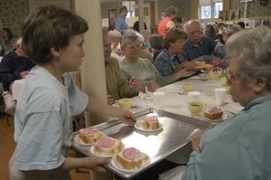 Church supper at the First Congregational Church, Whately: young boy delivering dessert to a table