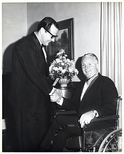 Mayor John F. Collins wearing medal and shaking hands with unidentified man