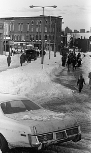 Pedestrians and vehicles on snowy Blue Hill Avenue and Warren Street