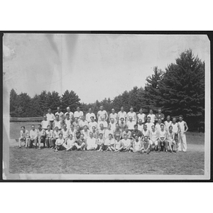 Group portrait of campers and staff on field in front of trees at unidentified YMCA camp