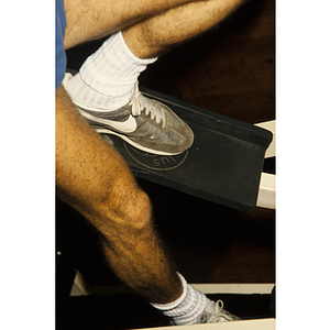 Man presses his foot down on an exercise machine