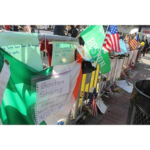 "Boston Strong" sign and various other signs and flags at Boston Marathon memorial