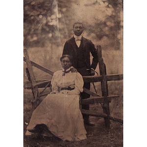 An African American couple posing by a fence