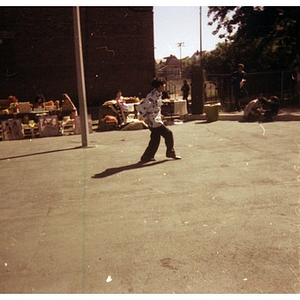 Young man dancing or running at a Latino Street festival; in the background, people are selling Latin American decorative arts and crafts at tables
