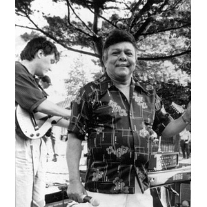 Singer on an outdoor stage with one of the musicians visible behind him.