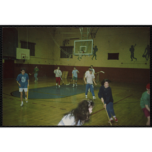 Teenage girls and boys play floor hockey