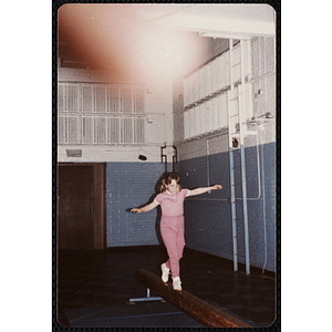 A girl walks across a balance beam at the Charlestown gymnasium