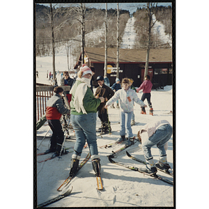 Children gather on skis at the base of a mountain at a resort