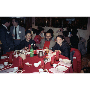 Rep. Byron Rushing smiles with two women at a restaurant table during a celebration of the Lunar New Year hosted by the Chinese Progressive Association