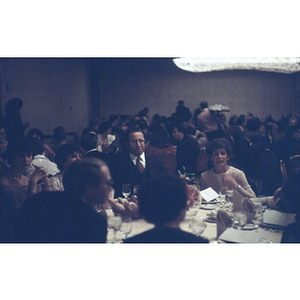 Tables of diners in a crowded hall at an unidentified formal event