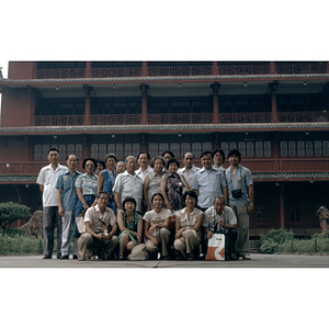 Male and Female Association members pose in a group in front of a red building