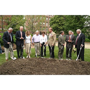 Nine people hold shovels before breaking ground for the Veterans Memorial