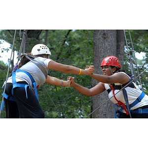 Nadia Alvarez and Ana Hidalgo hang onto each other on the Torch Scholars Project Adventure Ropes Course