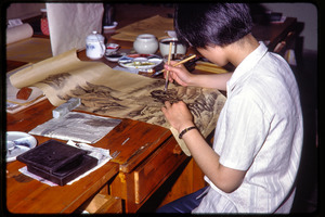 Arts and crafts factory: woman painting scenery in ink on a scroll