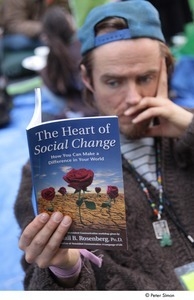 Occupy Wall Street: man reading book called, 'The Heart of Social Change'