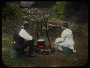 Man and woman cooking at a campfire