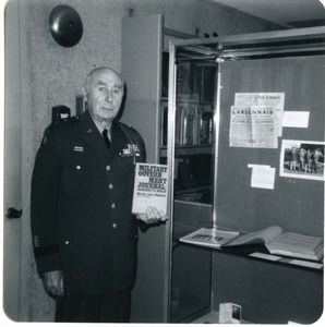 John J. Maginnis, in uniform, holding a copy of his book Military Government Journal