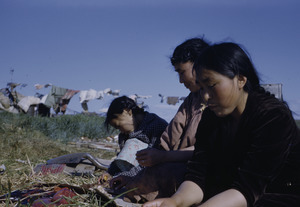 Women cutting up seal with clothes drying in background