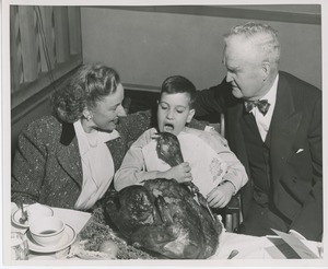 Connie Boswell and Bruce Barton with young client eating Thanksgiving turkey