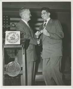 Bruce Barton shaking hands with and handing diploma to a client at Institute Day