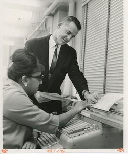 Unidentified man looking over a woman's work in a comptroller's office