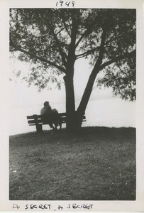 Unidentified man and woman embracing on a wooden bench