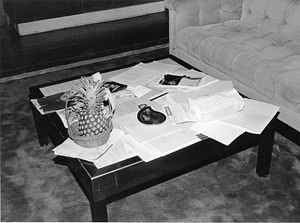 Coffee table littered with papers and fruit