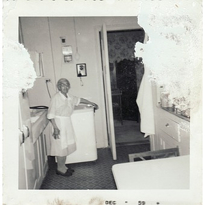 An elderly housekeeper poses in the kitchen