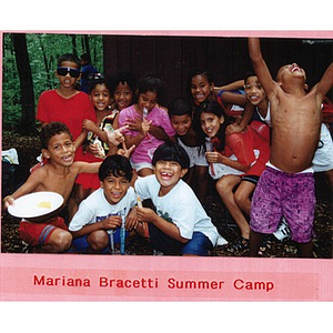 Twelve Latino children laughing, smiling at Mariana Bracetti Summer Camp; most of the children are holding candy or food in their hands