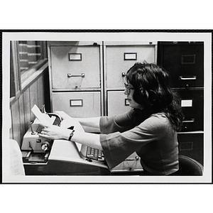 A female staff member placing a sheet of paper in the typewriter