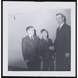 An unidentified man shakes hands with a boy at a Boys' Club of Boston St. Patrick's Day inaugural ball and exercises event